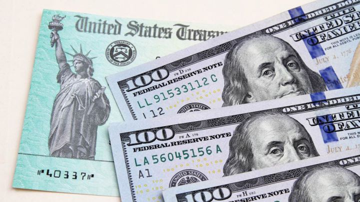 Cheque de estímulo de Estados Unidos y tres billetes de cien dólares estadounidenses