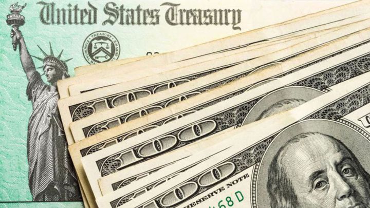 Cheque de estímulo de Estados Unidos y billetes de 100 dólares estadounidenses