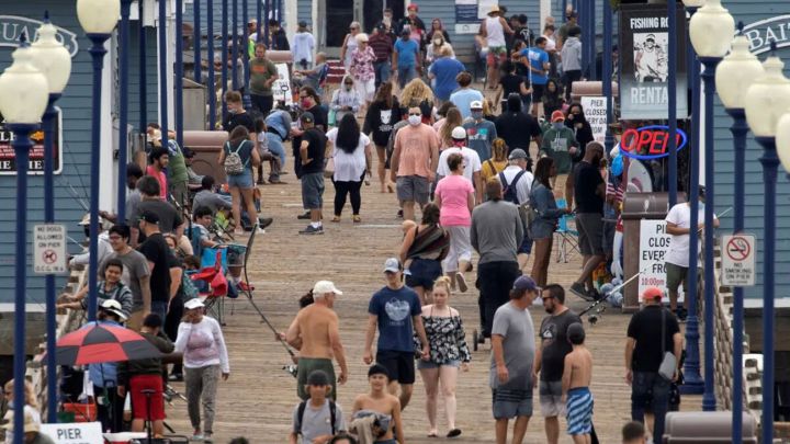 Pocas personas usan máscaras mientras caminan por un muelle en Oceanside, California