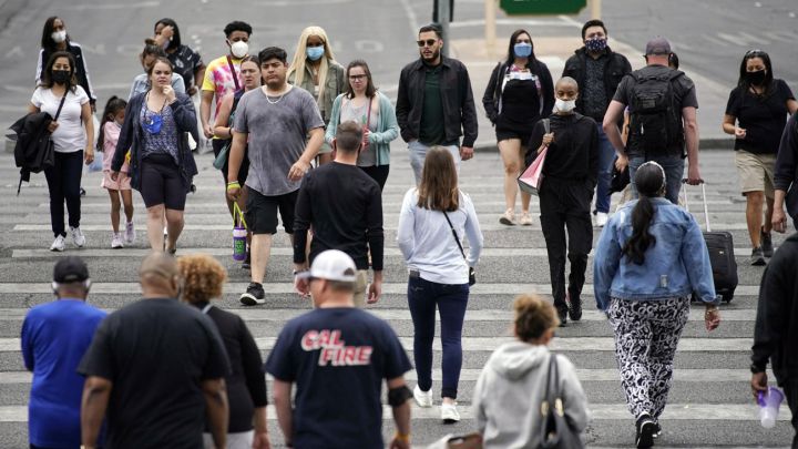 Personas sin y con mascarilla cruzando la calle