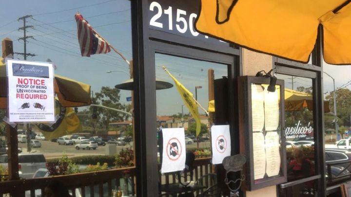 Anuncio en un restaurante pidiendo a los cliente presentar pruebas de no vacunación para ingresar