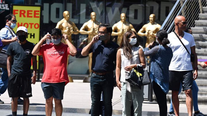 Personas usando mascarilla esperando para cruzar una calle en Hollywood