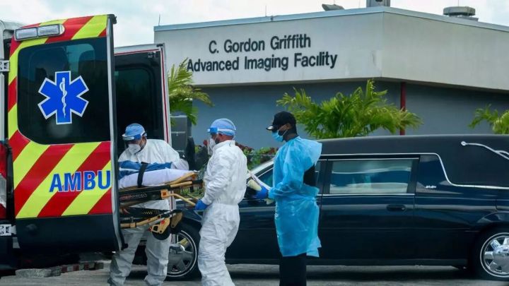 Personal de emergencias médicas llega con un paciente, mientras un auto funerario comienza a partir del North Shore Medical Center, donde se trata a los pacientes Covid-19, en Miami, Florida