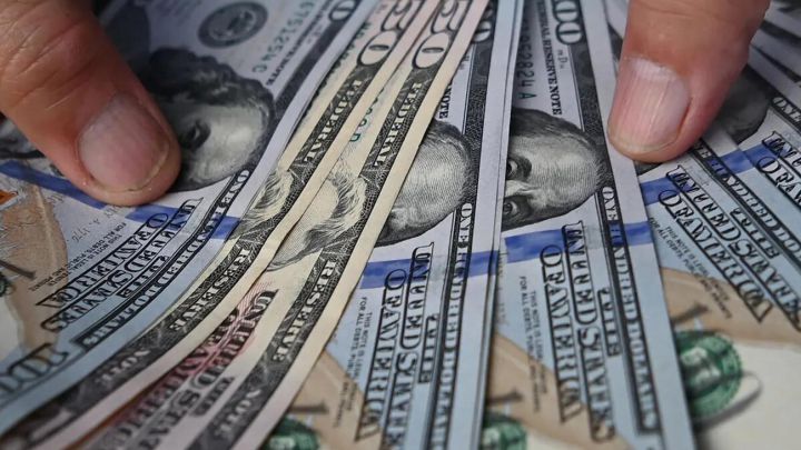 Mano sosteniendo billetes de 50 y 100 dólares estadounidenses