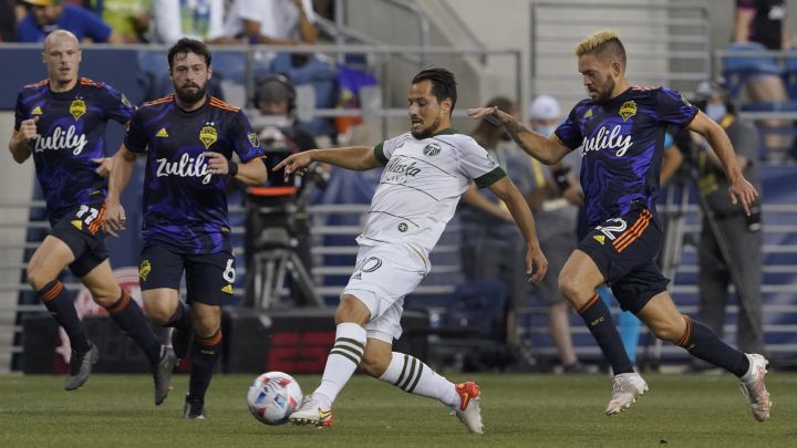 Sebastián Blanco buscando puntear el balón entre tres defensas de Seattle Sounders en juego con Portland Timbers.