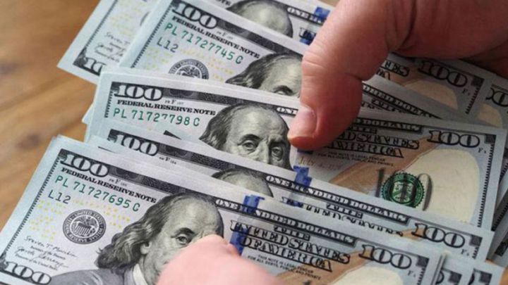Mano sosteniendo billetes de 100 dólares estadounidenses