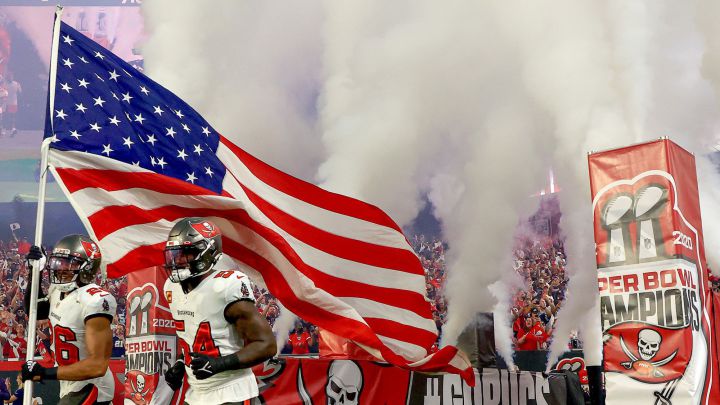 Jugadores de los Tampa Bay Buccaneers corren con la bandera estadounidense.