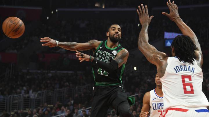 Kyrie Irving, base de los Boston Celtics, realiza un pase ante DeAndre Jordan, pívot de Los Angeles Clippers.