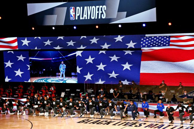Los jugadores de Milwaukee Bucks y Orlando Magic se arrodillan durante el himno de Estados Unidos.