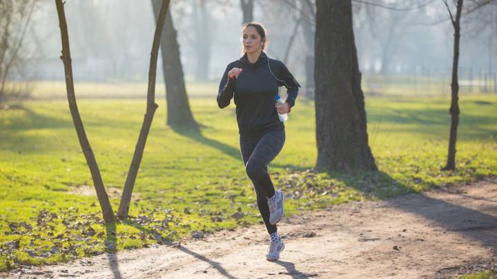 Chica haciendo running por un parque con frío