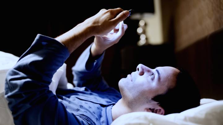 Hombre usando teléfono móvil en la cama