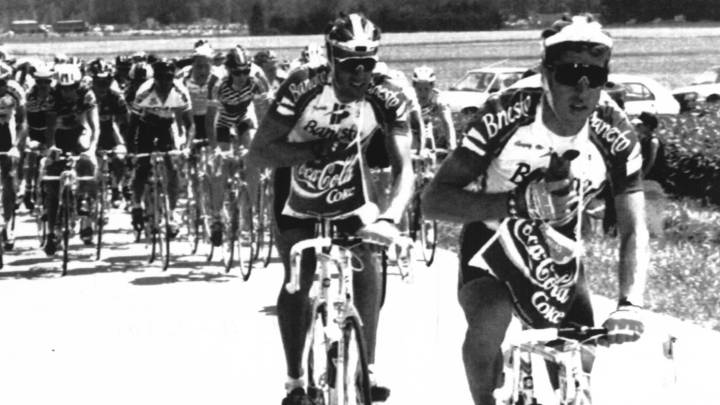 Perico Delgado y Miguel Indurain cogen bolsas de comida en el avituallamiento en el Tour de Francia de 1991.