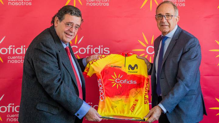 Joan Sitges, director general de Cofidis España, y José Luis López Cerrón, presidente de la Real Federación Española de Ciclismo, posan con un maillot de la selección española de ciclismo tras la renovación del acuerdo de colaboración entre ambas entidades.