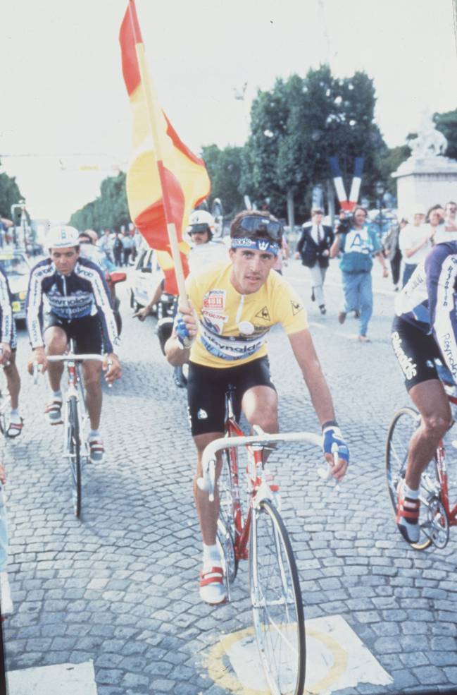 Perico Delgado, campeón del Tour de Francia en 1988, con la bandera de España y vestido de amarillo por los Campos Elíseos.