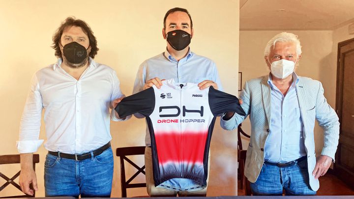 Marco Bellini, Pablo Flores Peña y Gianni Savio posan con un maillot tras la firma del acuerdo con la compañía Drone Hopper.