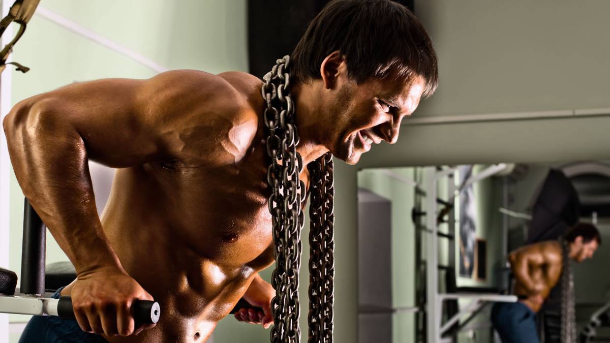 Entrenando en el gimnasio. Hombre con grandes músculos levantando peso  mientras entrena en el gimnasio. Ponerse en forma. Photos