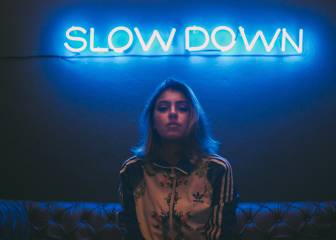 Una mujer posa bajo un neón azul de luz.