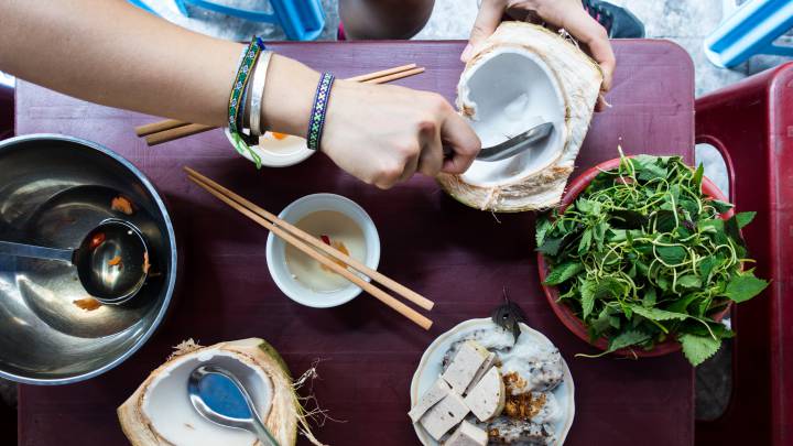 Una persona come coco y otros alimentos en un mercado vietnamita.