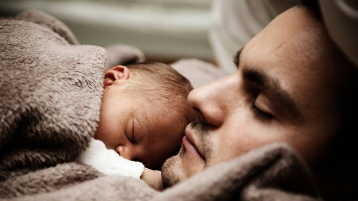 Un padre duerme con su bebé.