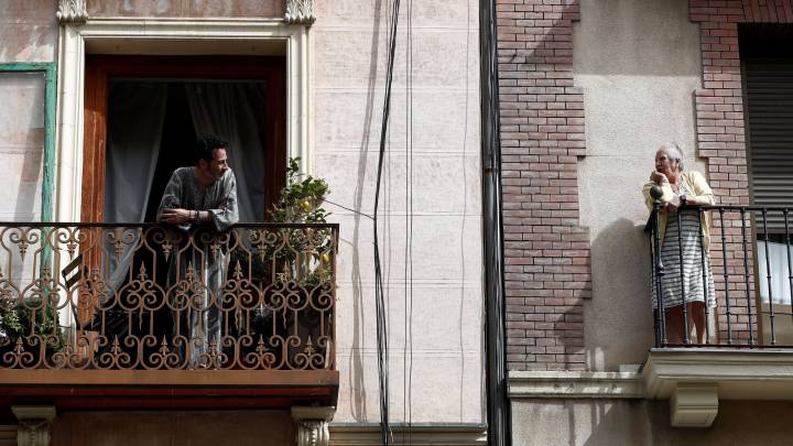 Dos vecinos conversan en el balcón de sus casas en Madrid este jueves durante la cuarta jornada laboral de aislamiento por el coronavirus.