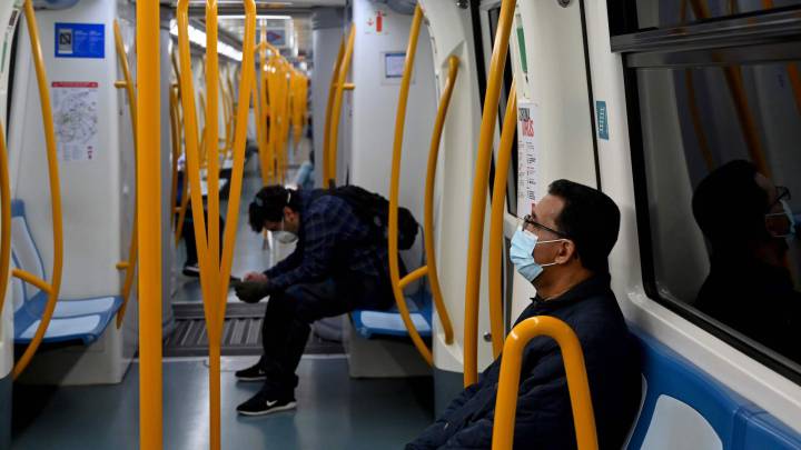 Dos pasajeros viajan protegidos con mascarillas y guardando el distanciamiento social en un vagón del Metro de Madrid.