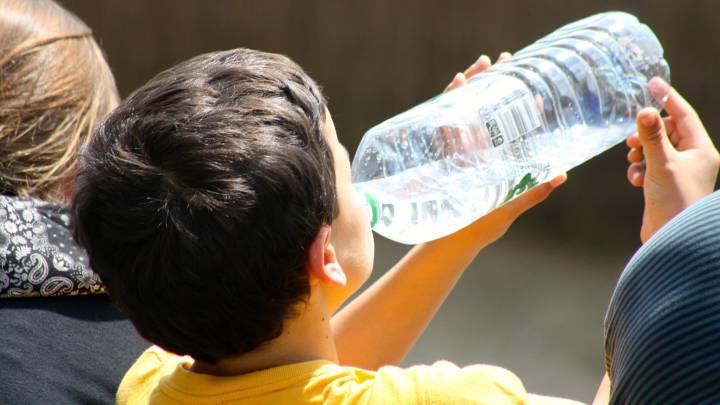 Un niño bebe agua en una botella