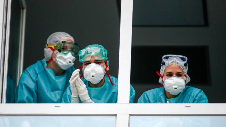 Varios sanitarios con protección EPI, mascarillas, gafas y guantes, saludan desde el Hospital Fundación Jiménez Díaz