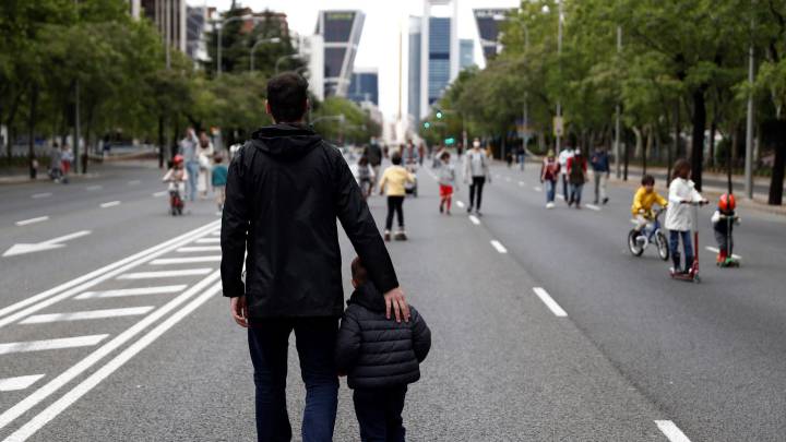 Un hombre pasea con su hijo por el Paseo de la Castellana en Madrid.
