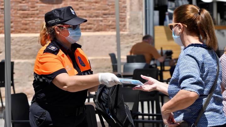 Una persona de Protección Civil reparte mascarillas a varias personas en Almería.