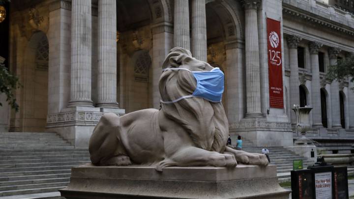 La estatua situada en el exterior de la Biblioteca Pública de Nueva York lleva mascarilla para una campaña durante la pandemia de la COVID-19