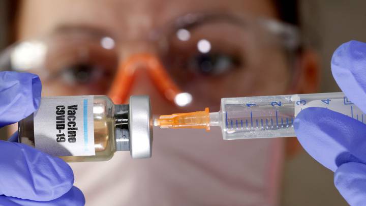 Una mujer coge un frasco con el rótulo de vacuna contra el coronavirus.