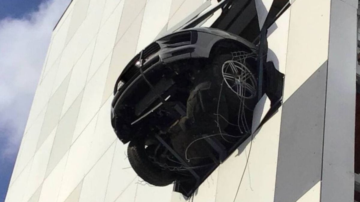 A Porsche is hanging in the air after crossing the wall of the parking lot