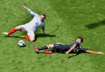 El centrocampista galés Joe Ledley disputando el balón con el inglés Rooney.