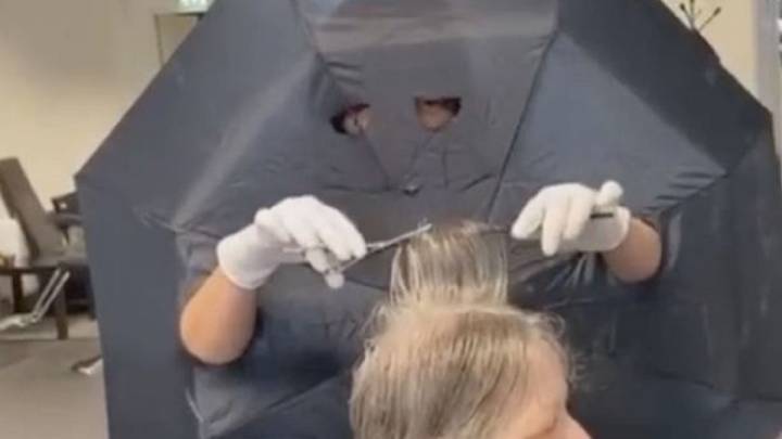 Una peluquera hace agujeros en un paraguas para poner una 'barrera' con sus clientes