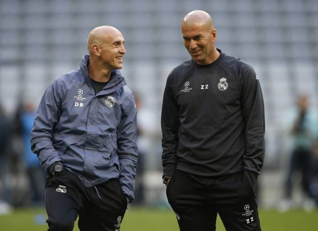 Zidane conversa con su ayudante sobre el césped del Allianz Arena en el entrenamiento previo al Bayern-Real Madrid de la Champions 2016-2017.