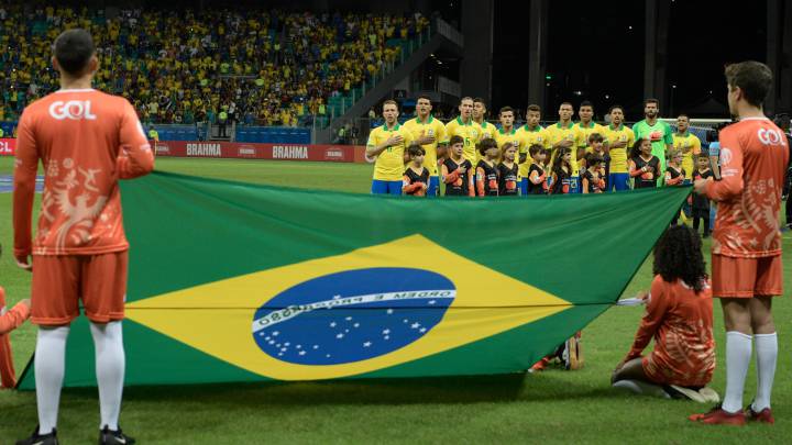 La selección brasileña canta el himno ante la bandera de su país.