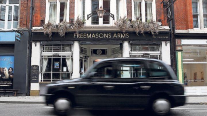 Un taxi londinense pasa por delante del histórico Freemasons Arms.