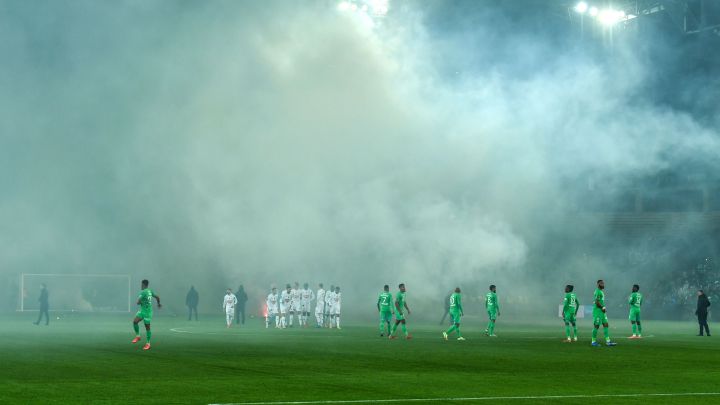 Los jugadores de AS Saint-Etienne y SCO Angers esperan tras el lanzamiento de bengalas por parte de los aficionados en el estadio Geoffroy Guichard.