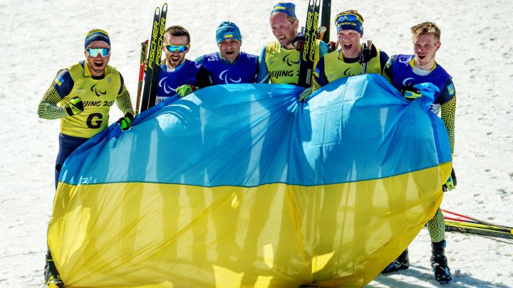 Los ucranianos Anatolii Kovalevskyi y su guía Oleksandr Mukshyn, Vitalii Lukianenko y su guía Borys Babar, y Dmytro Suiarko y su guía Oleksandr Nikonovych posan con la bandera de Ucrania tras ganar el bronce, el oro y la plata en biatlón en los Juegos Paralímpicos de Invierno de Pekín 2022.