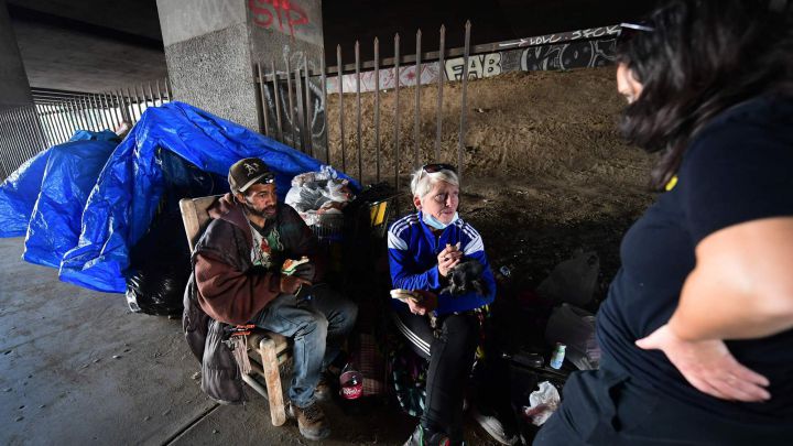 Dos sintecho hablan con una activista tras el desalojo de un campamento de personas sin hogar por parte de las autoridades de Los Ángeles cerca del SoFi Stadium, sede de la Super Bowl LVI.