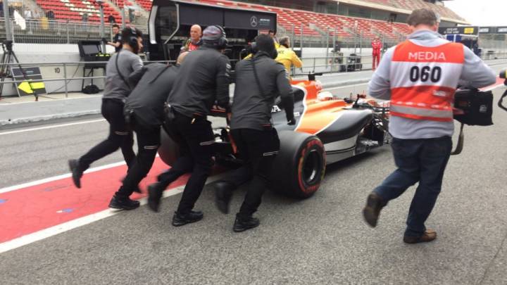 Los mecánicos de McLaren empujando el coche de Vandoorne.