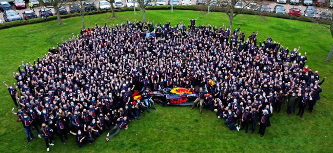 El piloto neerlandés Max Verstappen posa sentado en el neumático delantero de su coche, con todos los miembros del equipo Red Bull, como flamante campeón del mundo 2021 de Fórmula 1 en la sede del equipo austriaco situada en Milton Keynes. En la rueda trasera, el jefe del equipo, Christian Horner.