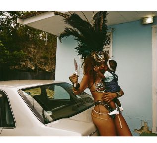 Rihanna sostiene en un brazo a un bebé mientras le abanica con la otra mano