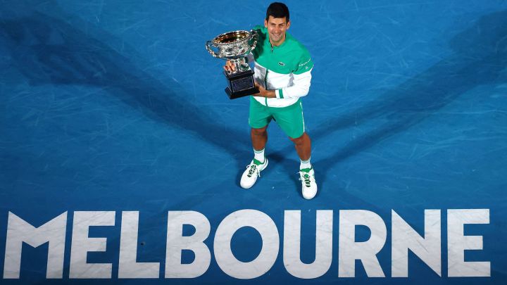 (FILES) In this file photo taken on February 21, 2021, Serbia's Novak Djokovic holds the Norman Brookes Challenge Cup trophy after beating Russia's Daniil Medvedev to win their men's singles final match on day fourteen of the Australian Open tennis tournament in Melbourne.  - World number one Novak Djokovic said on January 4, 2022 that he was heading to the Australian Open to defend his title after being granted a medical exemption to play.  (Photo by Patrick HAMILTON / AFP) / - IMAGE RESTRICTED TO EDITORIAL USE - STRICTLY NO COMMERCIAL USE -