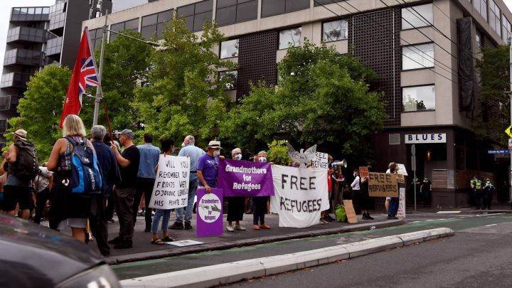 People hold placards up at a government detention center where Serbia's tennis champion Novak Djokovic is reported to be staying in Melbourne on January 7, 2022, after Australia said it had canceled the entry visa of Djokovic, opening the way to his detention and deportation in a dramatic reversal for the tennis world number one.  (Photo by William WEST / AFP)