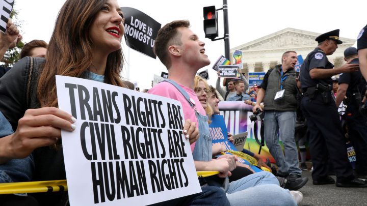 LGBTQ activists and supporters block the street outside the U.S. Supreme Court as it hears arguments in a major LGBT rights case in Washington